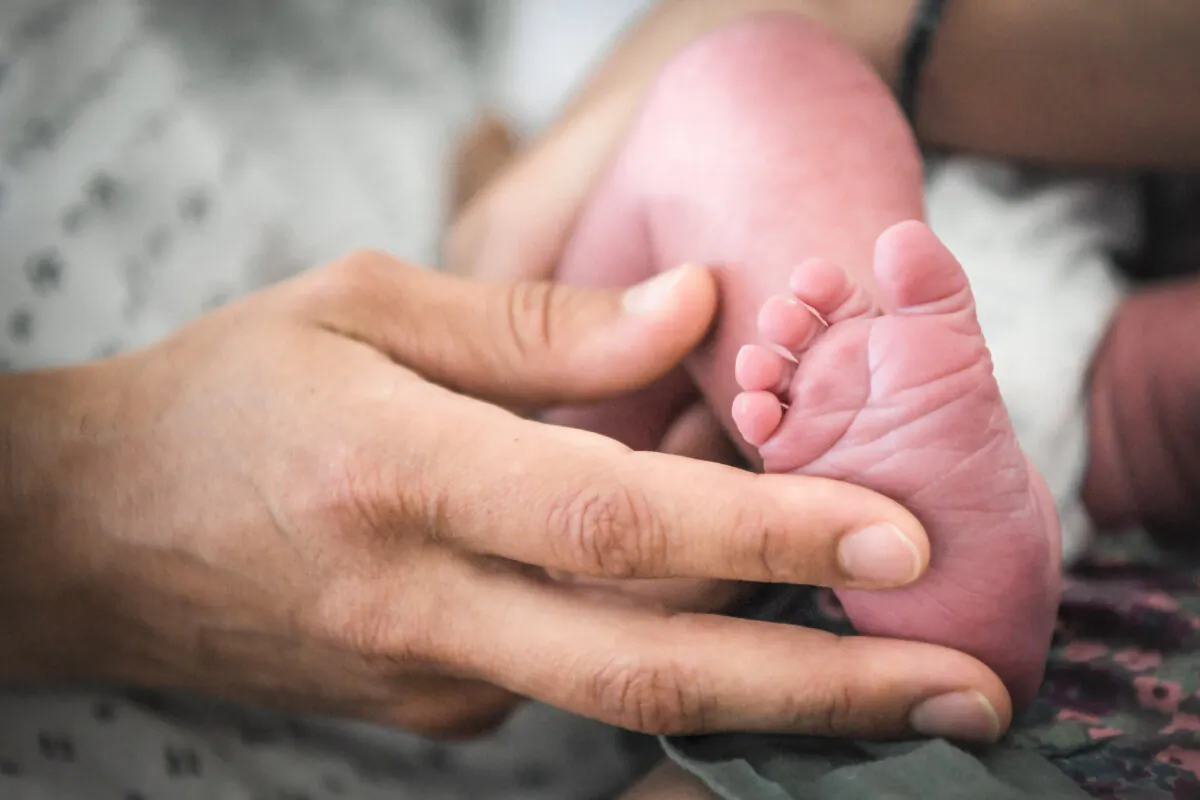 A woman holds the foot of a baby in a file photo. (Loic Venance/AFP via Getty Images)