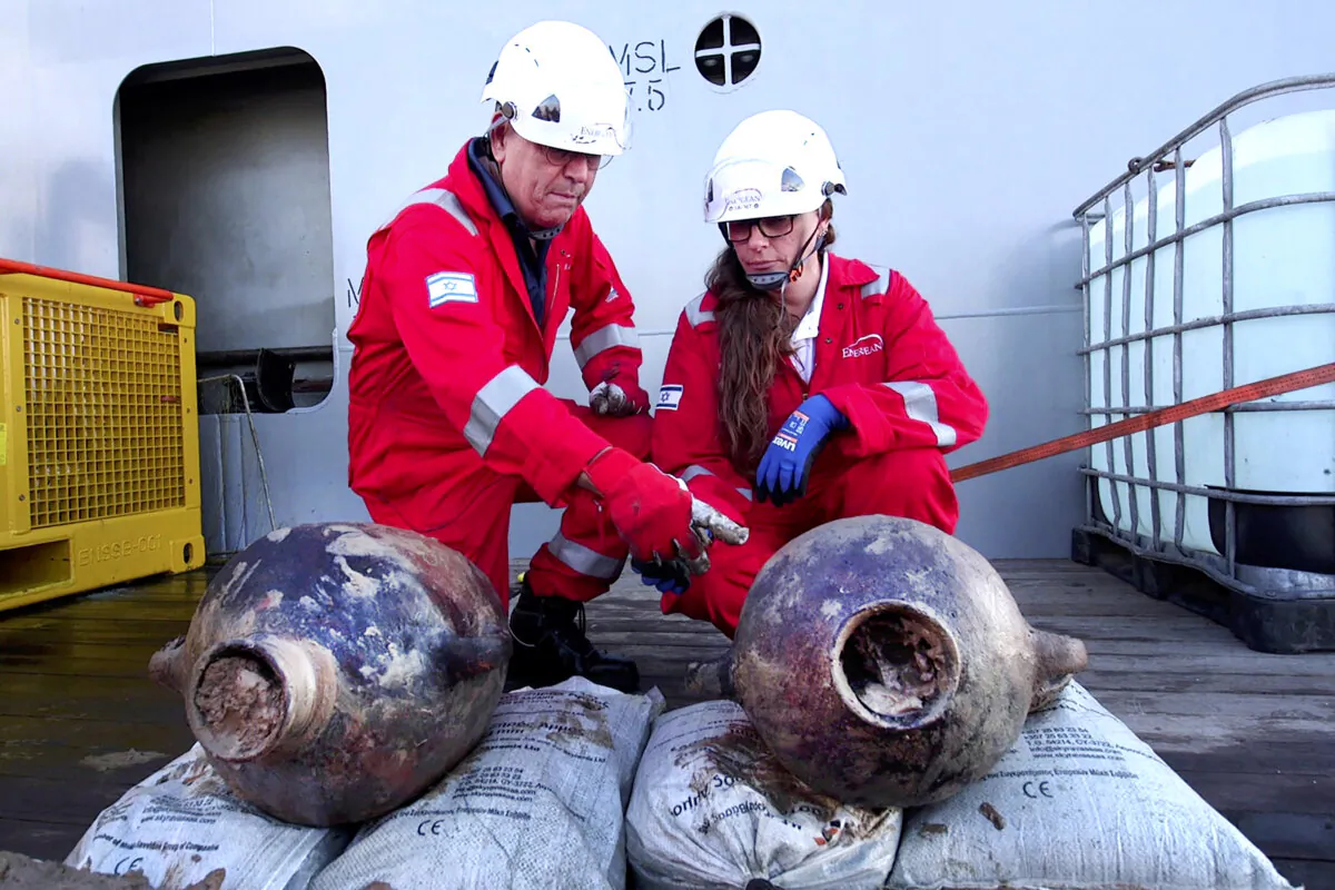 Jacob Sharvit (L) and Dr. Karnit Bahartan with the ancient jars that were carried on the world's oldest known deep-sea ship, as seen some 55.9 miles (90 kilometers) off the Israeli coastline, in a photo released on June 20, 2024. (Emil Aladjem/Israel Antiquities Authority via AP)