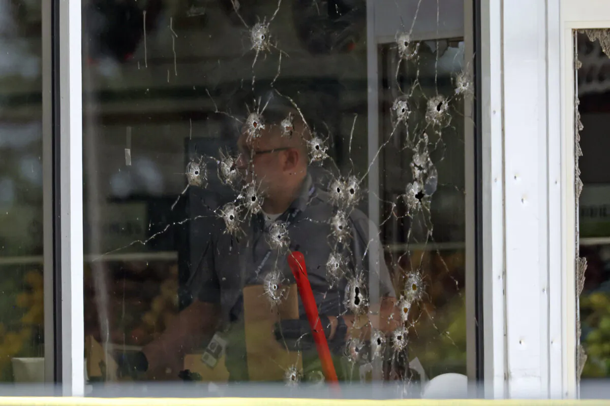 Damage can be seen to a front window as law enforcement officers work the scene of a shooting at the Mad Butcher grocery store in Fordyce, Ark., on June 21, 2024. (Colin Murphey/Arkansas Democrat-Gazette via AP)