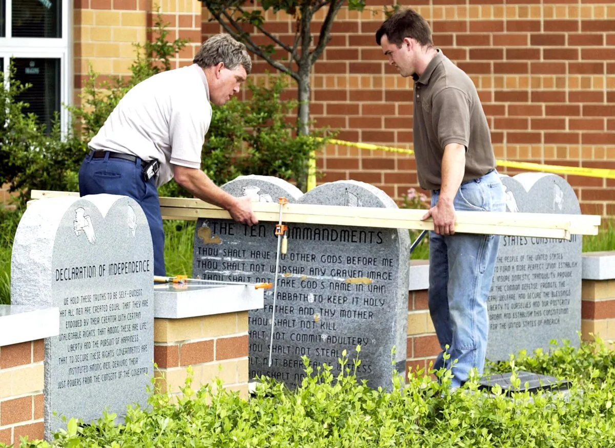 Workers remove a monument bearing the Ten Commandments outside West Union High School in West Union, Ohio, on June 9, 2003. (Al Behrman/AP Photo)
