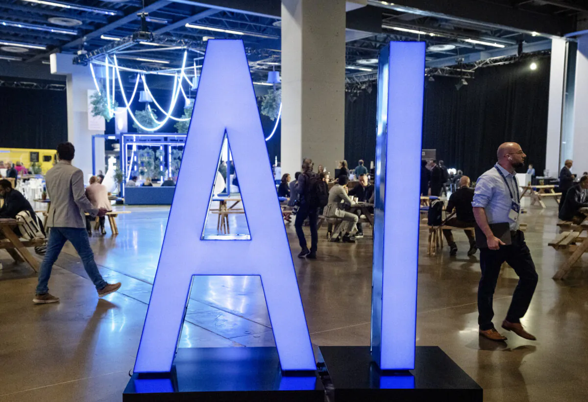 People walk past an AI sign at the All In artificial intelligence conference in Montreal on Sept. 28, 2023. (The Canadian Press/Ryan Remiorz)