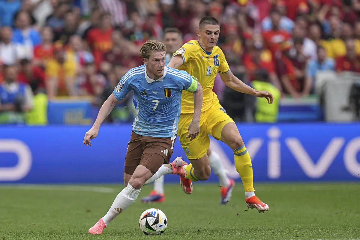 Belgium's Kevin De Bruyne (L) fights for the ball with Ukraine's Vitaliy Mykolenko during a Group E match between Ukraine and Belgium at the Euro 2024 soccer tournament in Stuttgart, Germany, on June 26, 2024. (Ariel Schalit/AP Photo)