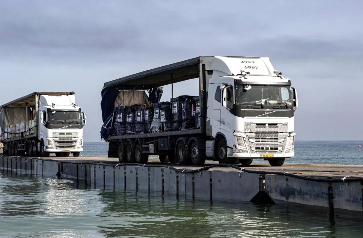 Trucks loaded with humanitarian aid from the United Arab Emirates and the United States Agency for International Development cross the Trident Pier before arriving on the beach on the Gaza Strip on May 17, 2024. (Staff Sgt. Malcolm Cohens-Ashley/U.S. Army via AP)