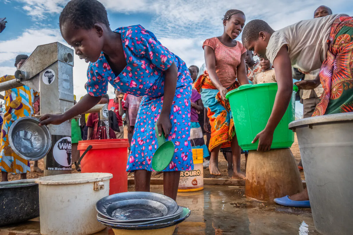 Villagers enjoy clean water from a well built by Water Wells for Africa on July 6, 2018. (John Fredricks/The Epoch Times)