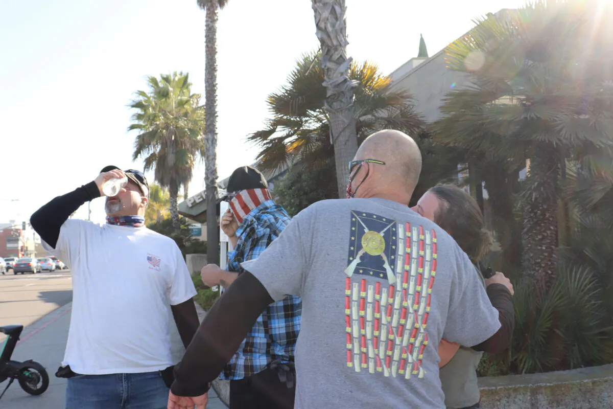 A Patriot March participant washes his eyes after being sprayed by attackers at San Diego's Pacific Beach on Jan. 9, 2021. (Tina Deng/The Epoch Times)