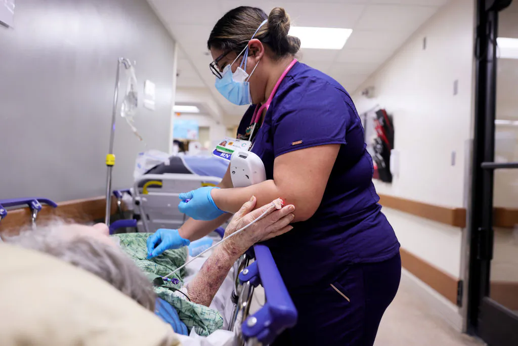 A registered nurse cares for a patient on a stretcher in a hallway of the Emergency Room at Providence St. Mary Medical Center in Apple Valley, Calif., on Jan. 5, 2021. (Mario Tama/Getty Images)