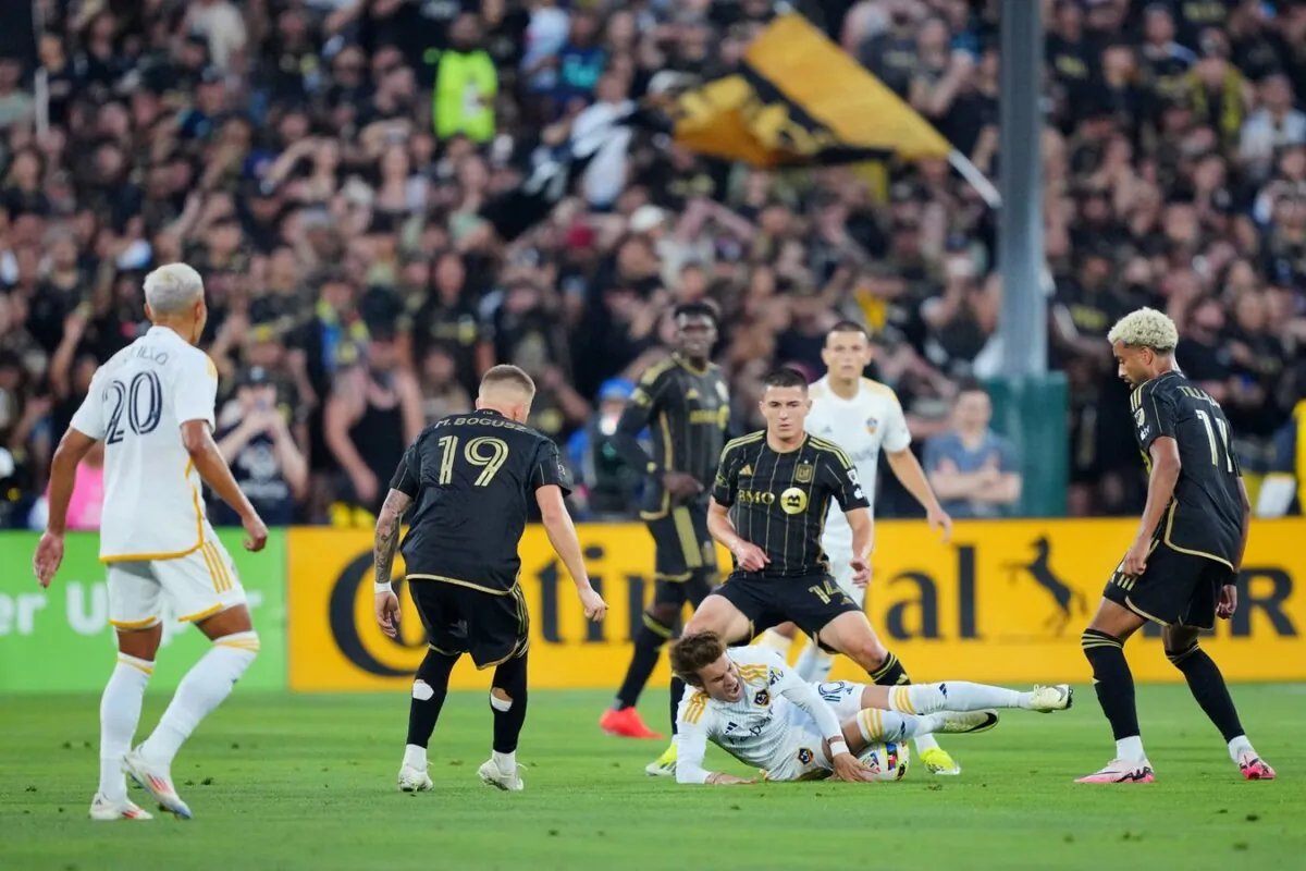 LA Galaxy midfielder Riqui Puig (10) reacts while falling to the pitch as LAFC defender Sergi Palencia (14) looks on during the first half at Rose Bowl in Pasadena, Calif., on July 4, 2024 (Kirby Lee/USA TODAY Sports via Field Level Media)