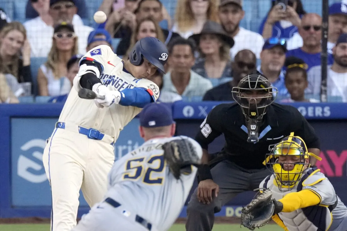 Los Angeles Dodgers' Shohei Ohtani (L) hits a solo home run as Milwaukee Brewers relief pitcher Bryan Hudson (2nd L) and catcher William Contreras watch along with home plate umpire Edwin Moscoso during the eighth inning of a baseball game in Los Angeles on July 6, 2024. (Mark J. Terrill/AP Photo)