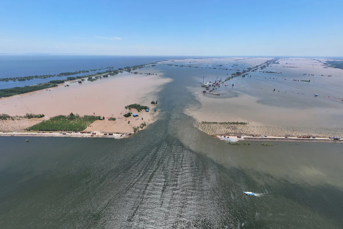 Water flows through a breach in the embankment on the shore of Dongting lake in Huarong county, in China's central Hunan province on July 6, 2024. (STR/AFP via Getty Images)