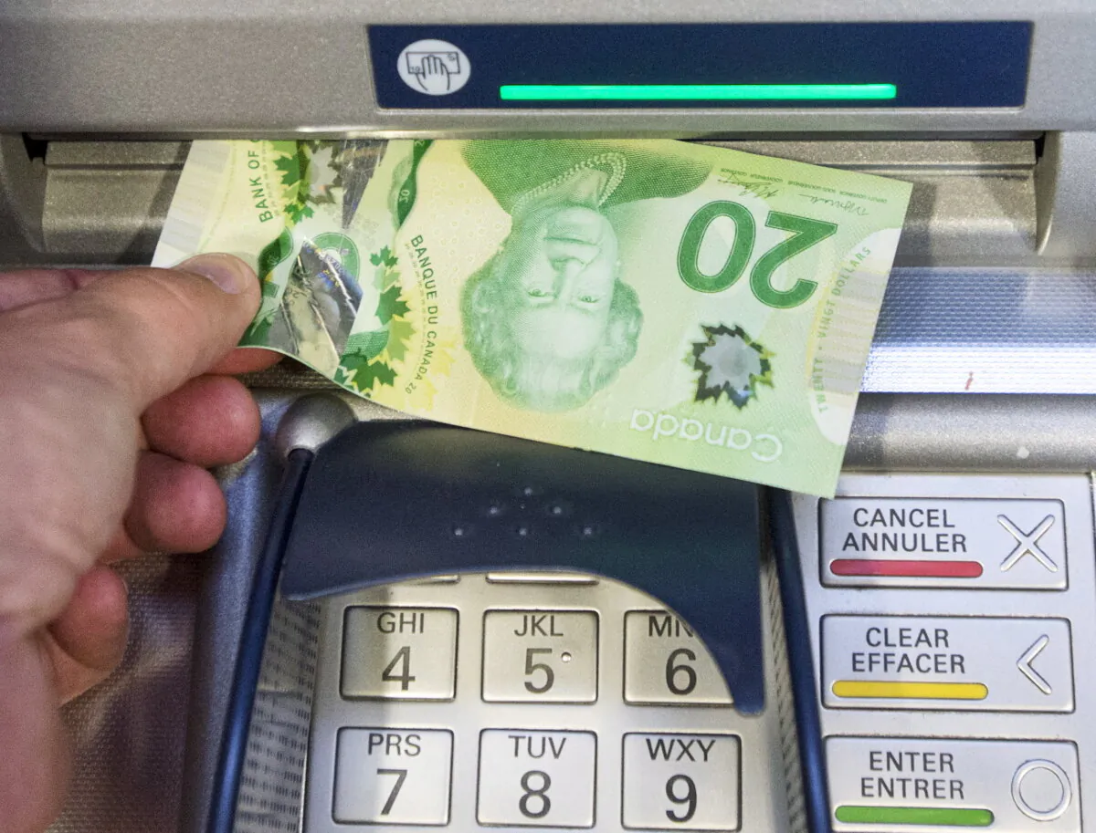 Money is removed from a bank machine in a photo illustration in Montreal, on May 30, 2016. (The Canadian Press/Ryan Remiorz)