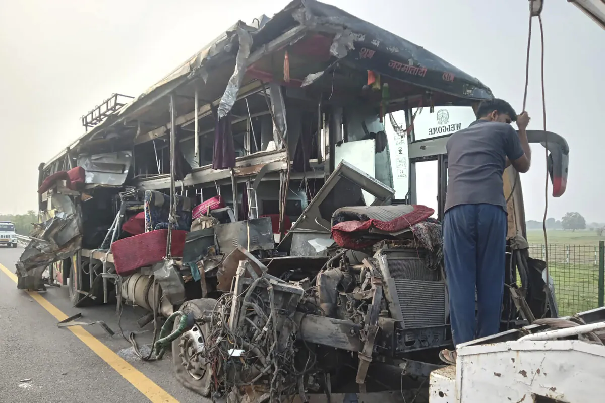 A roadside assistance worker tows away the mangled remains of a double-decker passenger bus that collided with a milk truck, near Unnao, in northern India state of Uttar Pradesh on July 10, 2024. (AP Photo)