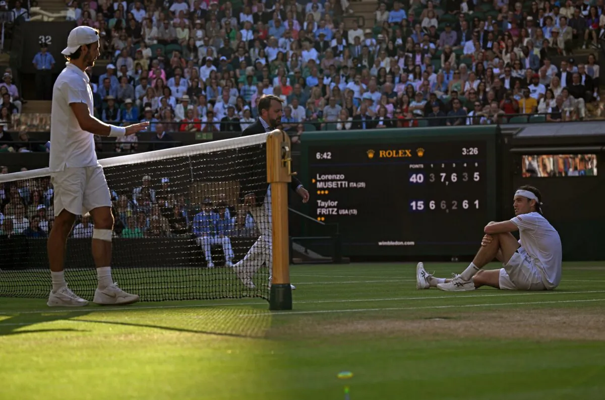 Taylor Fritz (R) sits on the court after slipping while attempting a return against Lorenzo Musetti during their Wimbledon quarterfinal match in London, on July 10, 2024. (Andrei Sakovic/AFP)