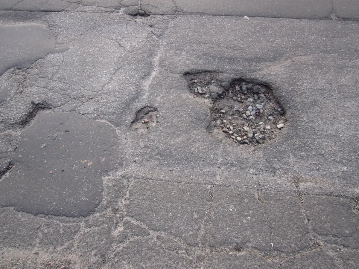 You can patch up the potholes on the driveway with a kit available at a home center. (ghrzuzudu/Shutterstock)