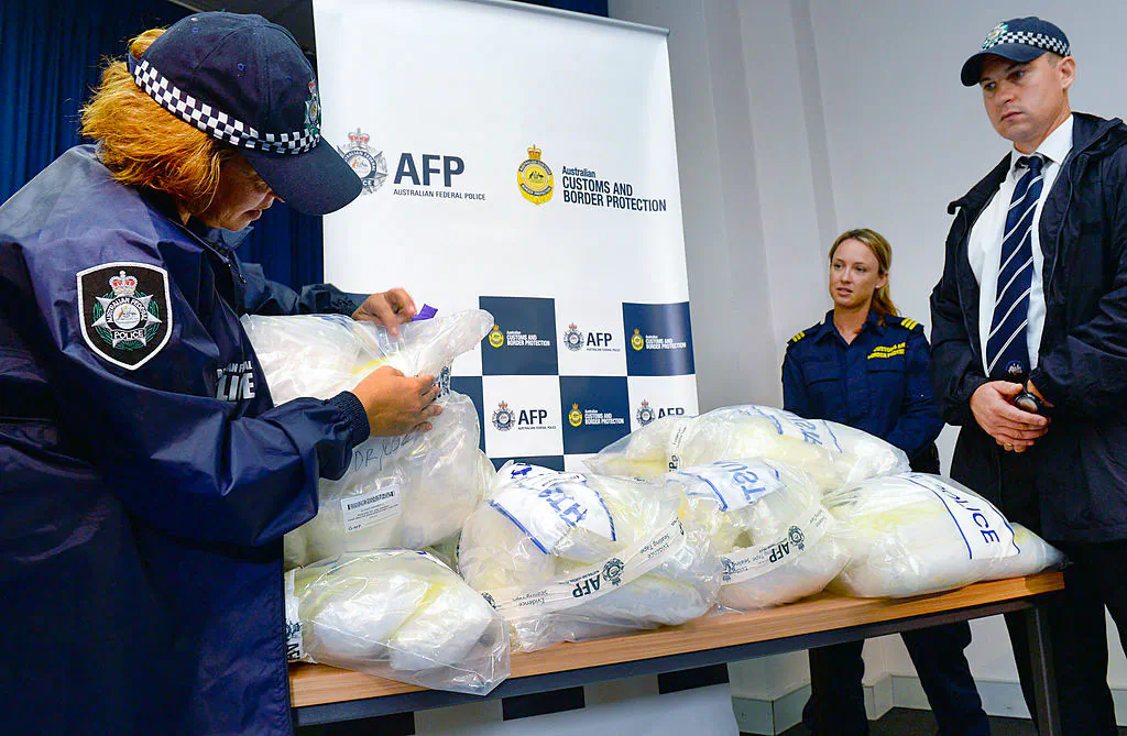 An Australian Federal Police officer (L) inspects seized methamphetamine after Australian authorities found Aus$180 million (US$162 million) of the drug stashed in a consignment of kayaks from China, in Sydney on Feb. 12, 2014. (William West/Getty Images)