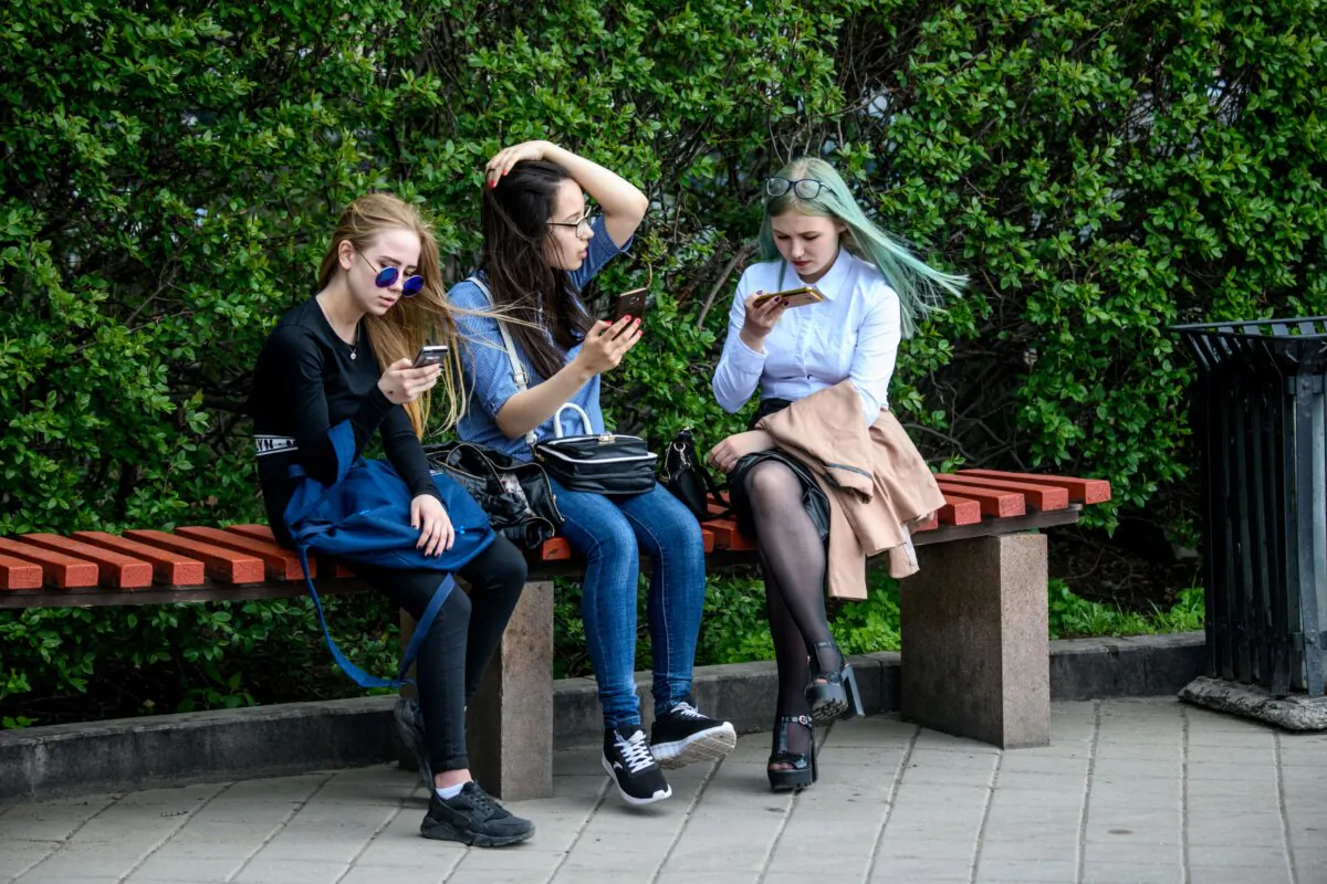 Girls use their smartphones while sitting on a bench in Yekaterinburg, Russia, on May 24, 2018. (Mladen Antonov/AFP via Getty Images)