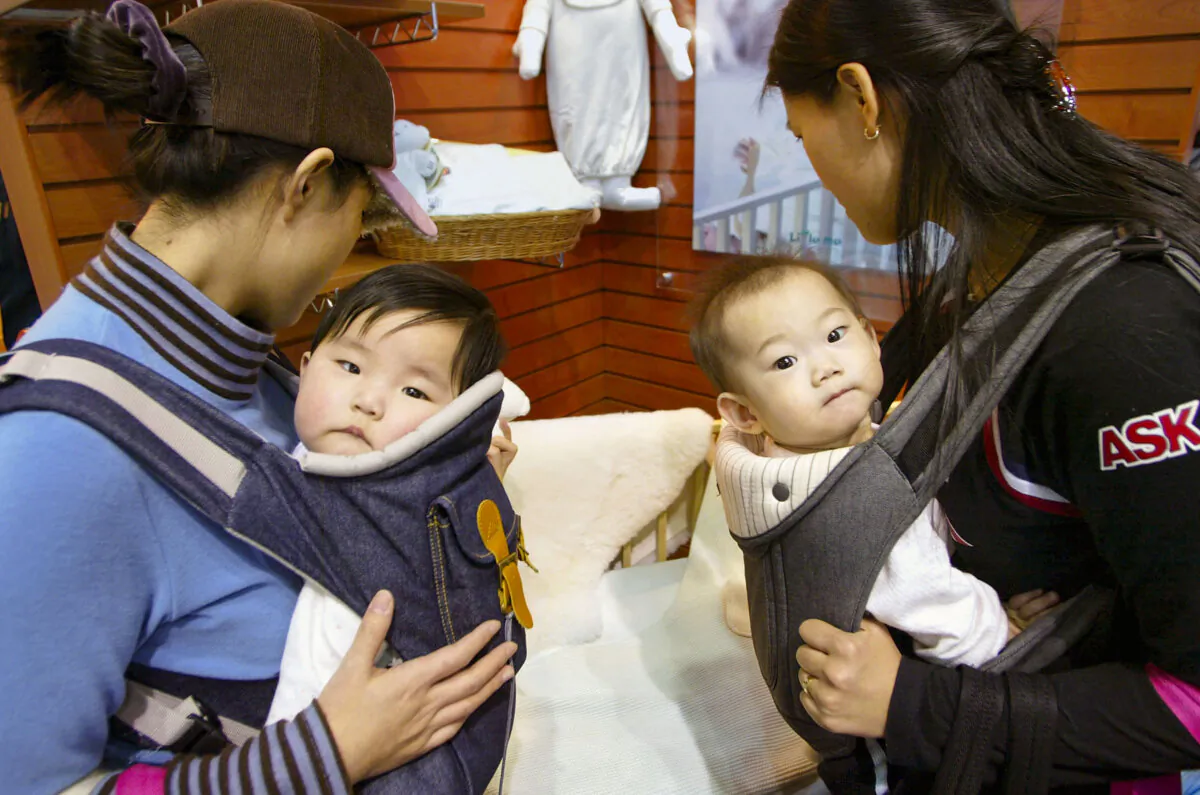 Two mothers carry their babies at a pregnancy and maternity exhibition in Seoul, South Korea on Feb. 17, 2005. (Chung Sung-Jun/Getty Images)
