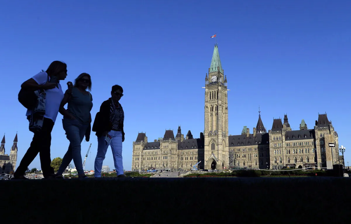 People walk past Parliament Hill in Ottawa, in a file photo. (The Canadian Press/Justin Tang)