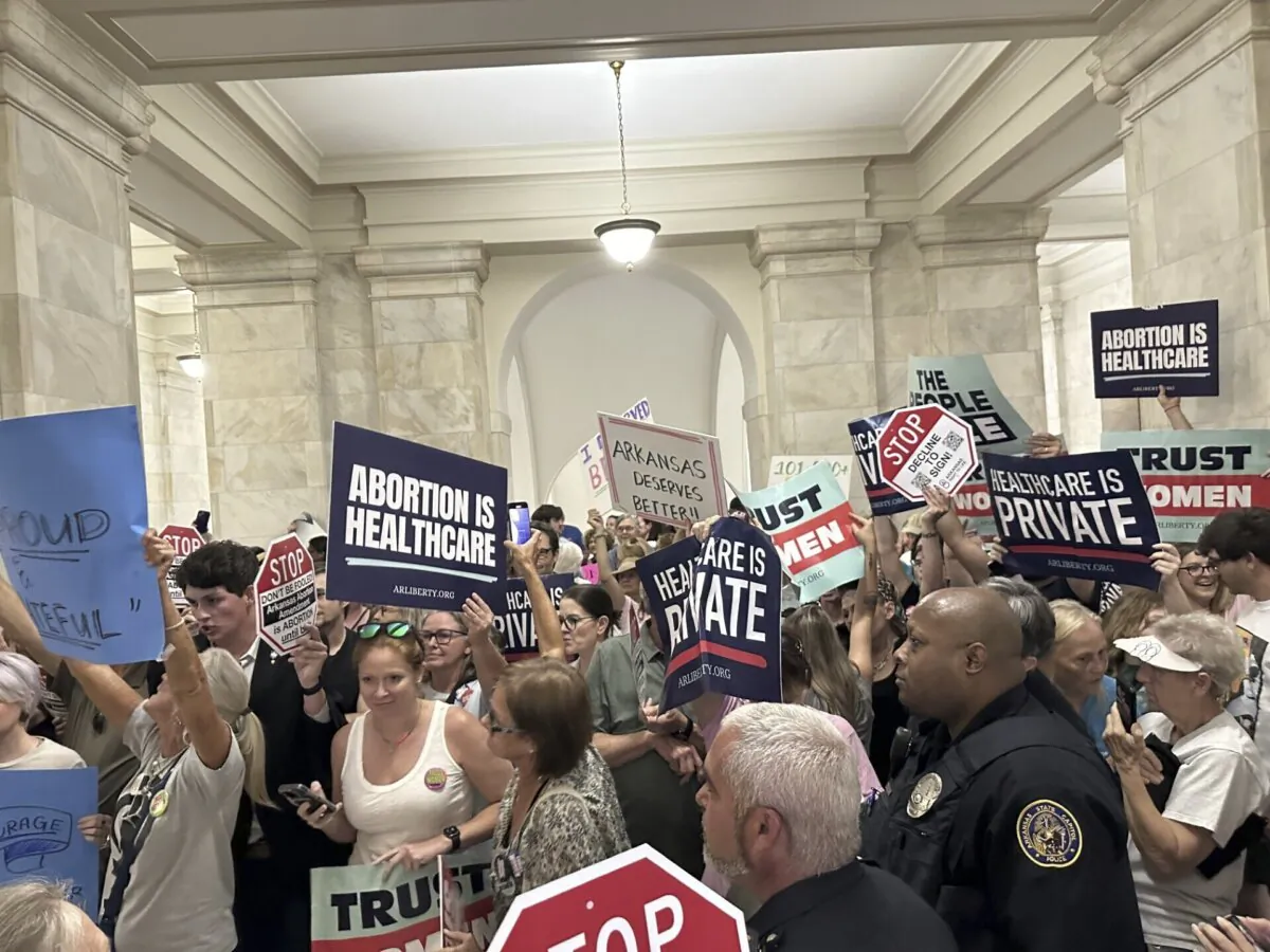 Supporters and opponents of a proposed ballot measure to scale back Arkansas' abortion ban hold signs outside the old Supreme Court chamber at the state Capitol in Little Rock, Ark., on July 5, 2024. (Andrew DeMillo/AP Photo)