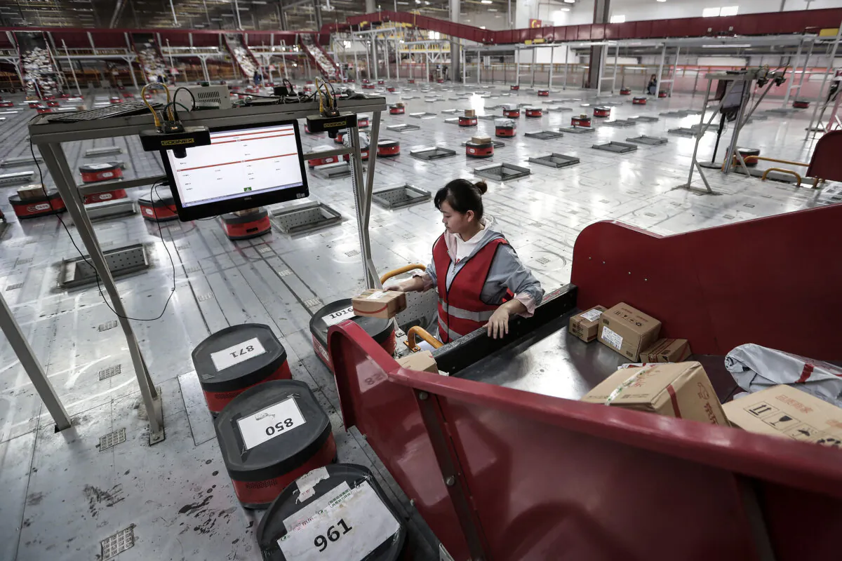 An employee transport parcels from Conveyor belt to automatic robot at the warehouse of a logistics base of JingDong Group in Wuhan, China, on Nov. 5, 2019. (Wang He/Getty Images)