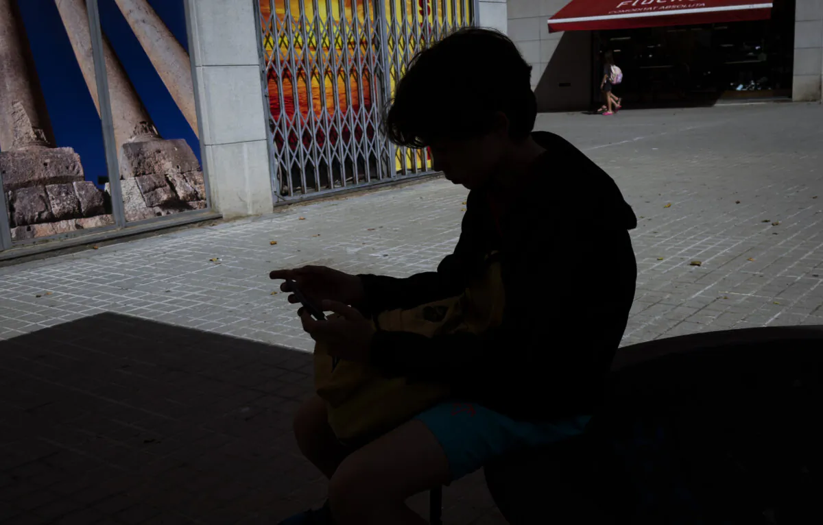 A 12-year-old boy on his personal phone outside school in Barcelona, Spain, on June 17, 2024. (Emilio Morenatti/AP Photo)