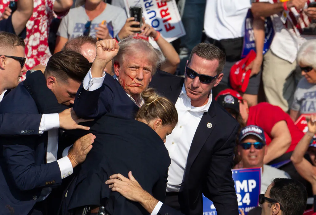 Republican candidate former President Donald Trump is seen with blood on his face surrounded by secret service agents as he is taken off the stage at a campaign event in Butler, Pa., on July 13, 2024. (Rebecca Droke/AFP via Getty Images)