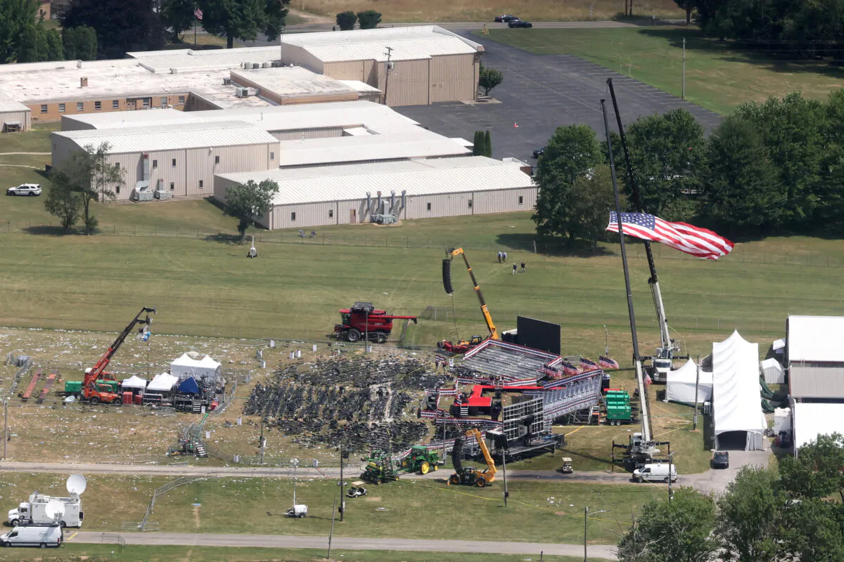 The stage where former President Donald Trump had been standing during an assassination attempt the day before, and the roof of a nearby building where a gunman was shot dead by law enforcement, in Butler, Pa., on July 14, 2024. (Brendan McDermid/Reuters)