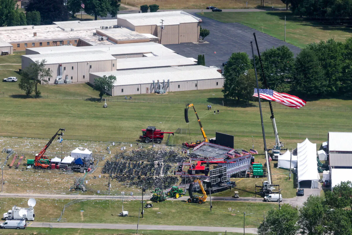 The stage where former President Donald Trump had been standing during an assassination attempt the day before, and the roof of a nearby building where a gunman was shot dead by law enforcement, in Butler, Pa., on July 14, 2024. (Brendan McDermid/Reuters)