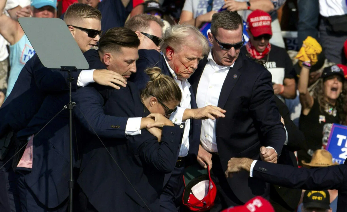 Former President Donald Trump with blood on his face surrounded by secret service agents as he is taken off the stage at a campaign event in Butler, Pa., on July 13, 2024. (Rebecca Droke/AFP via Getty Images)