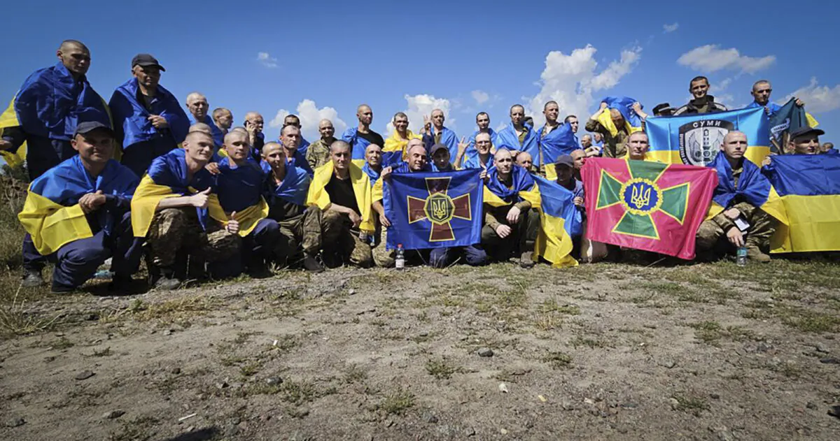 Ukrainian soldiers hold flags of their units after a prisoners exchange at an undisclosed location in Ukraine. (Ukrainian Presidential Press Office via AP)