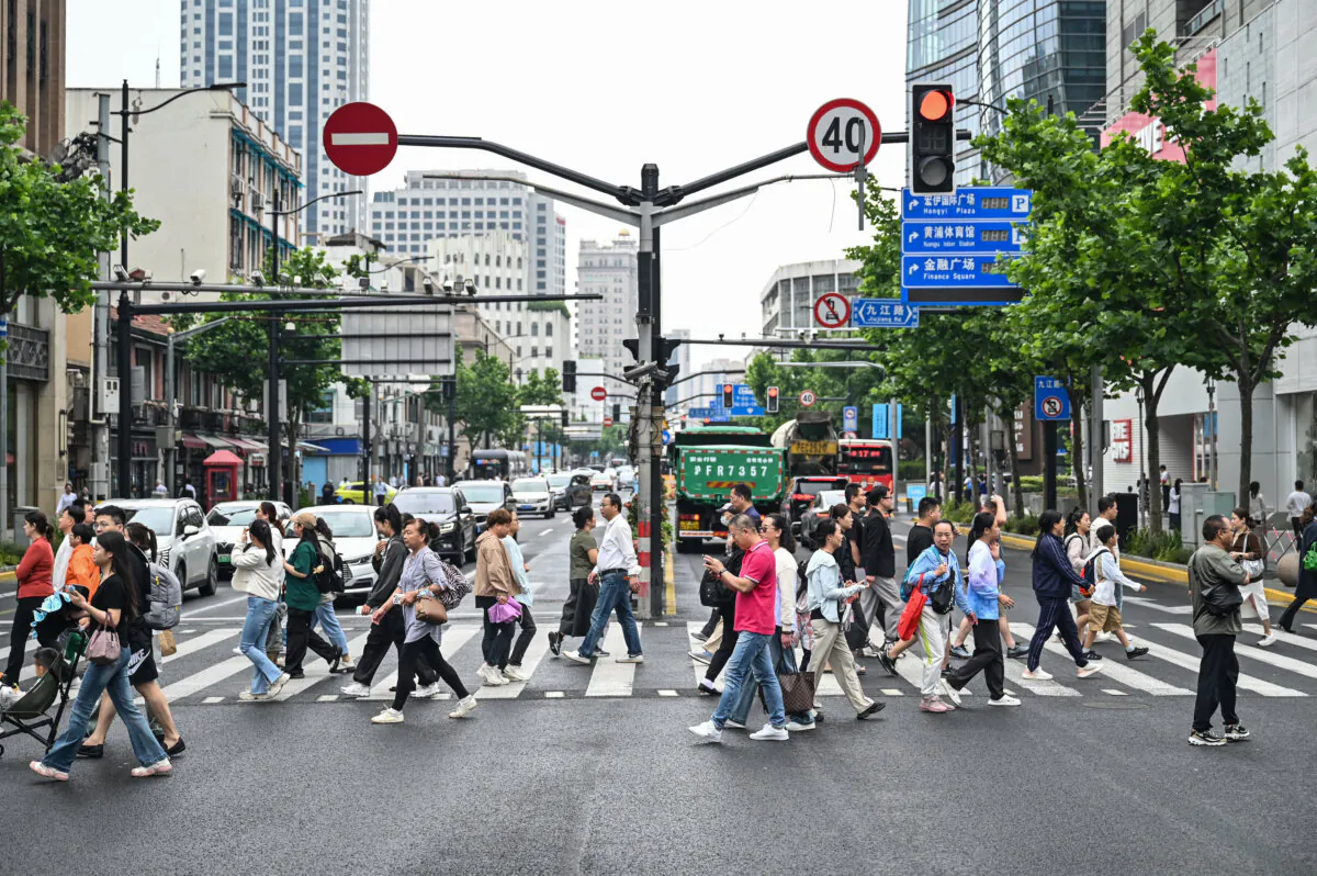 People cross a street at the Huangpu district in Shanghai on June 6, 2024. (Hector Retamal /AFP via Getty Images)