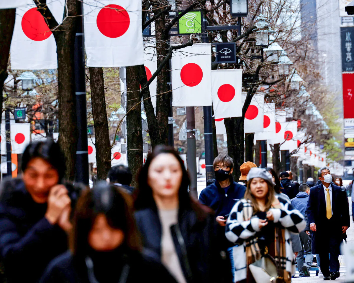 People walk past Japanese national flags in a shopping district in Tokyo on March 19, 2024. (Kim Kyung-Hoon/Reuters)
