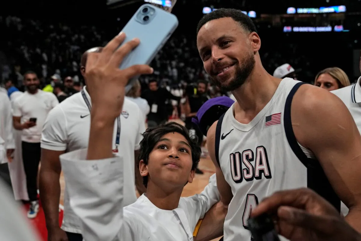 Stephen Curry of the U.S. men's basketball team poses for a selfie with a young fan after an exhibition game against Serbia in Abu Dhabi, United Arab Emirates, on July 17, 2024. (Altaf Qadri/AP Photo)