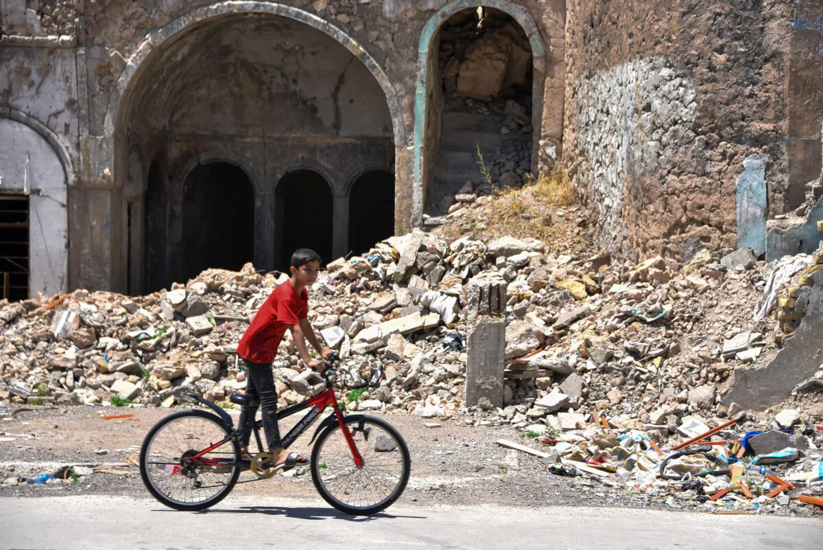 An Iraqi boy rides his bicycle across a building destroyed during the battles to defeat the Islamic State group, in the old city of Mosu, Iraq, on May 20, 2024. (Zaid AL-OBEIDI / AFP)