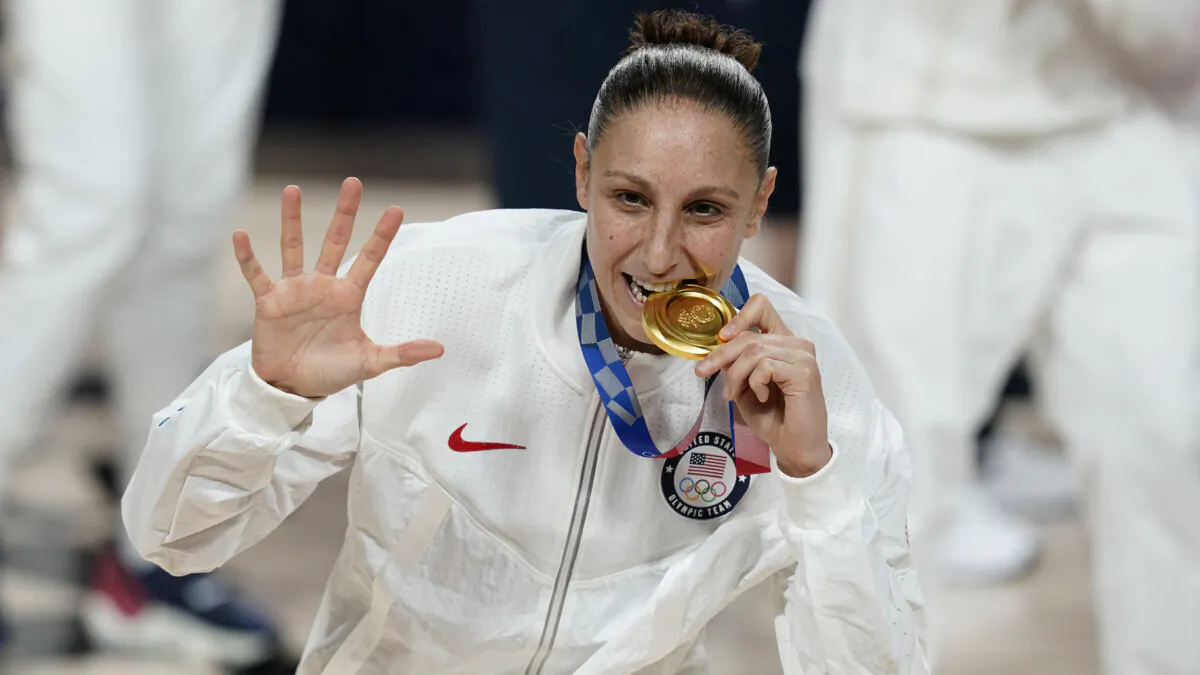 United States's Diana Taurasi bites her gold medal during the medal ceremony for women's basketball at the 2020 Summer Olympics in Saitama, Japan, on Aug. 8, 2021. (Charlie Neibergall/AP Photo)