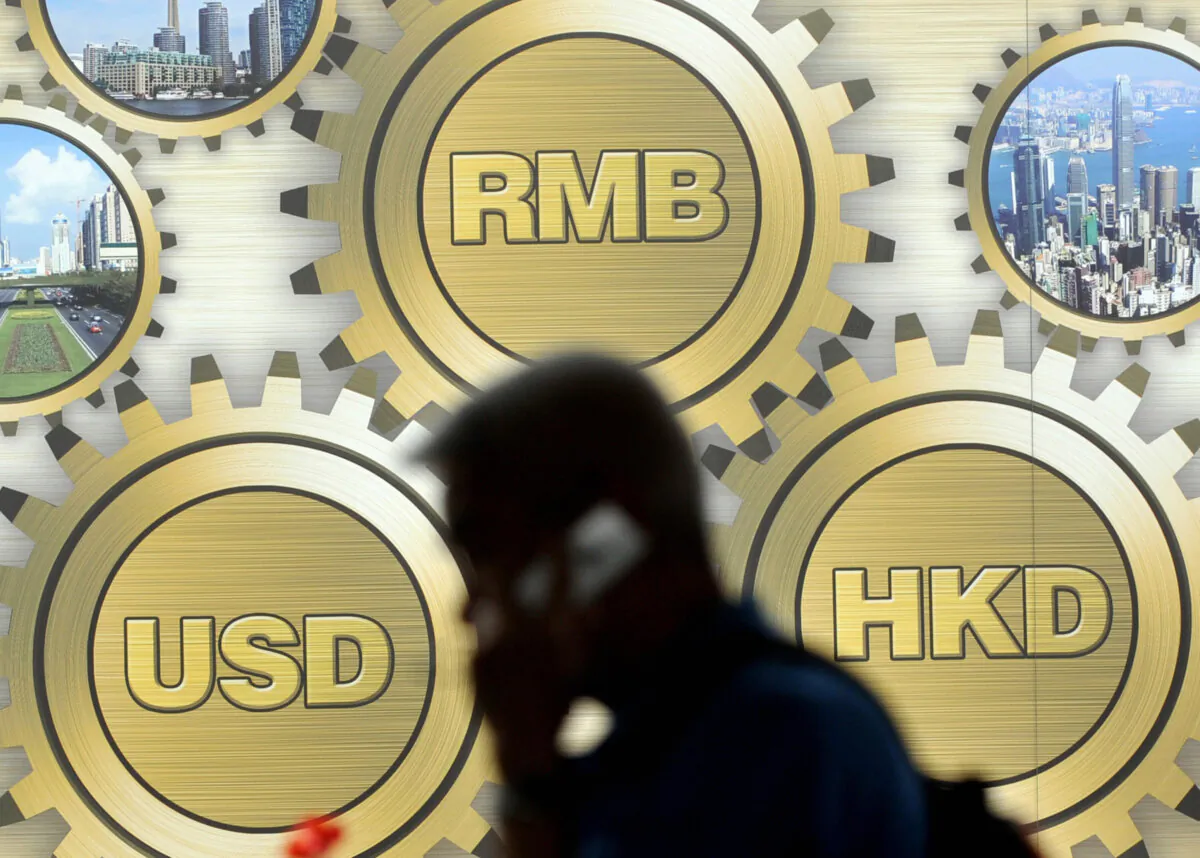 A pedestrian walks past a billboard showing Chinese yuan (top C), Hong Kong dollar (R) and U.S. dollar currency signs displayed in front of a building in Hong Kong on March 21, 2009. (Ted Aljibe/AFP via Getty Images)
