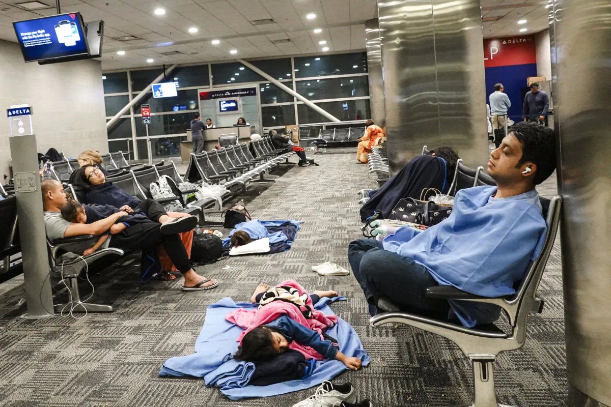 Travelers rest where they can in the McNamara terminal at the Detroit Metropolitan Wayne County Airport in Romulus, Mich., on July 21, 2024. (Joe Raedle/Getty Images)