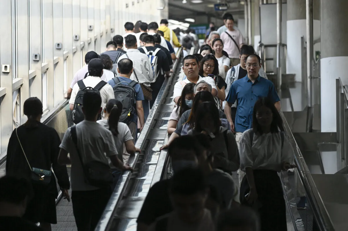 Commuters take escalators at a subway station in Beijing on July 10, 2024. (Wang Zhao/AFP via Getty Images)