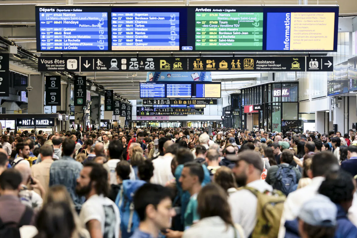 Passengers gather around the departure and arrival boards at the Gare Montparnasse train station as France's high-speed rail network was hit by malicious acts disrupting the transport system hours before the opening ceremony of the Paris 2024 Olympic Games, in Paris on July 26, 2024. (Thibaud Moritz/AFP via Getty Images)