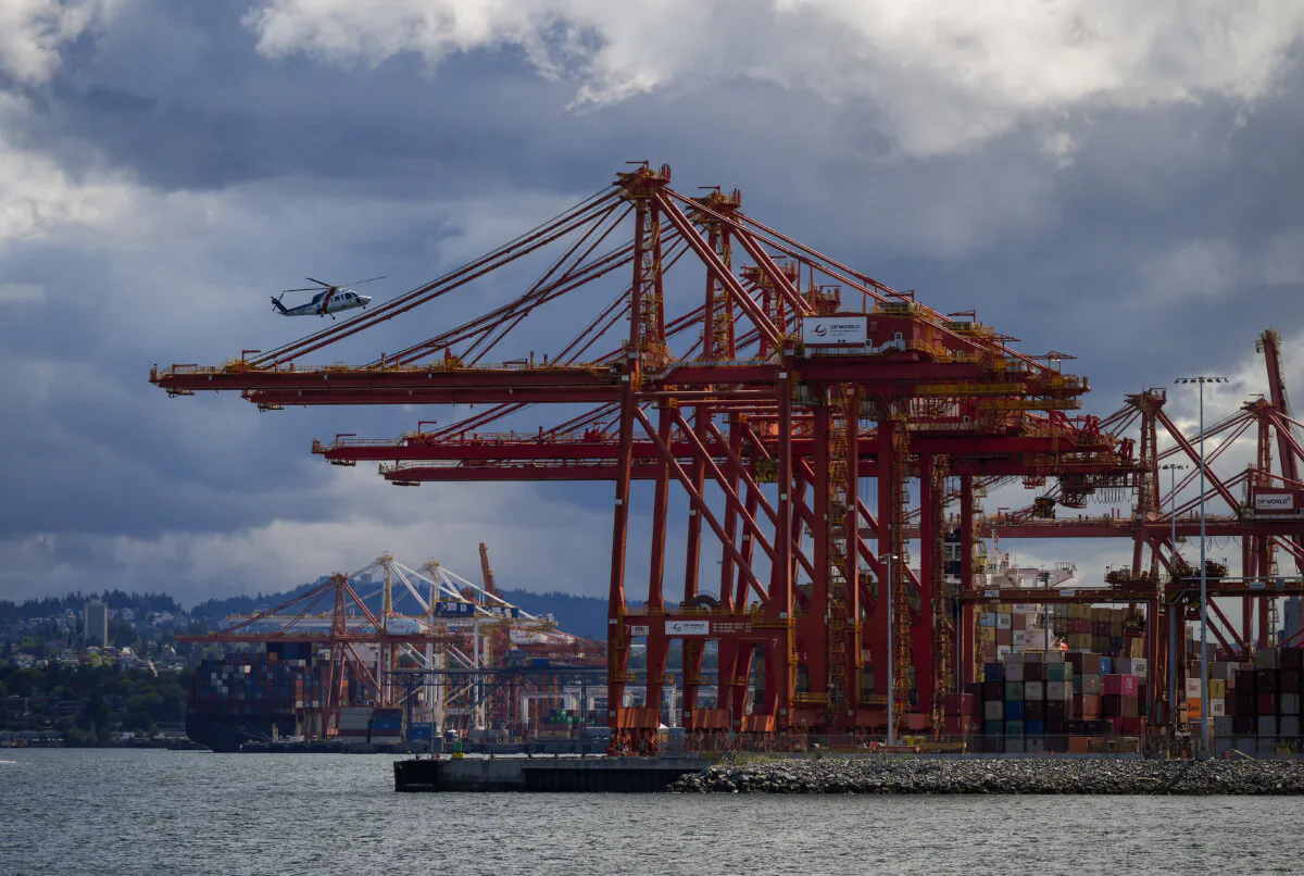 A BC Ambulance Service helicopter operated by Helijet passes gantry cranes used to load and unload cargo ships at port while preparing to land, in Vancouver, on July 25, 2024. (The Canadian Press/Darryl Dyck)