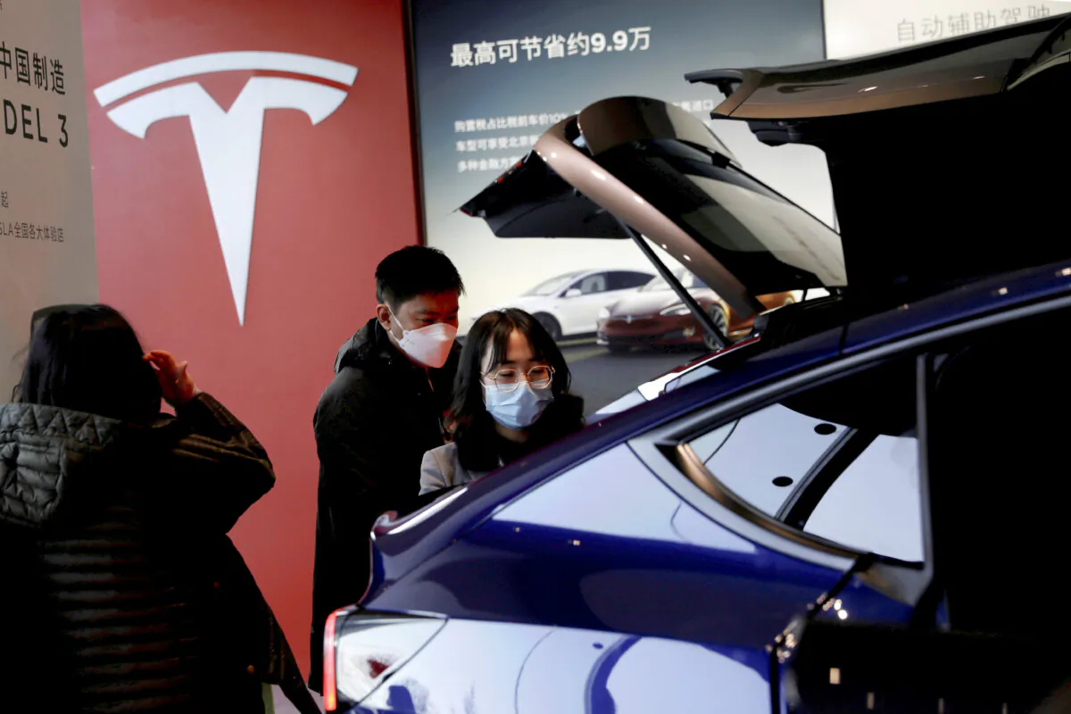 Visitors wearing face masks check a China-made Tesla Model Y sport utility vehicle (SUV) at the electric vehicle maker's showroom in Beijing on Jan. 5, 2021. (Tingshu Wang/Reuters)