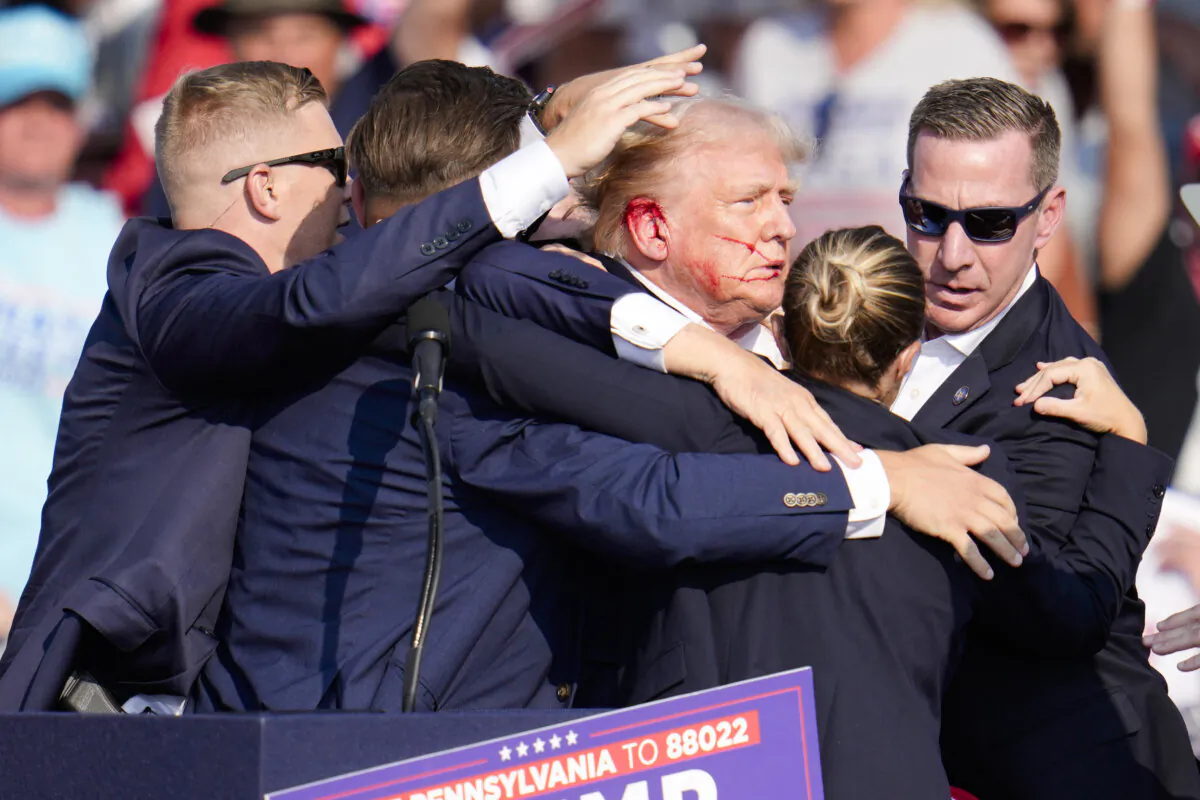 Republican presidential candidate and former President Donald Trump is surrounded by U.S. Secret Service agents as he is helped off the stage after an assassination attempt at a campaign rally in Butler, Pa., on July 13, 2024. (Gene J. Puskar/AP Photo) 