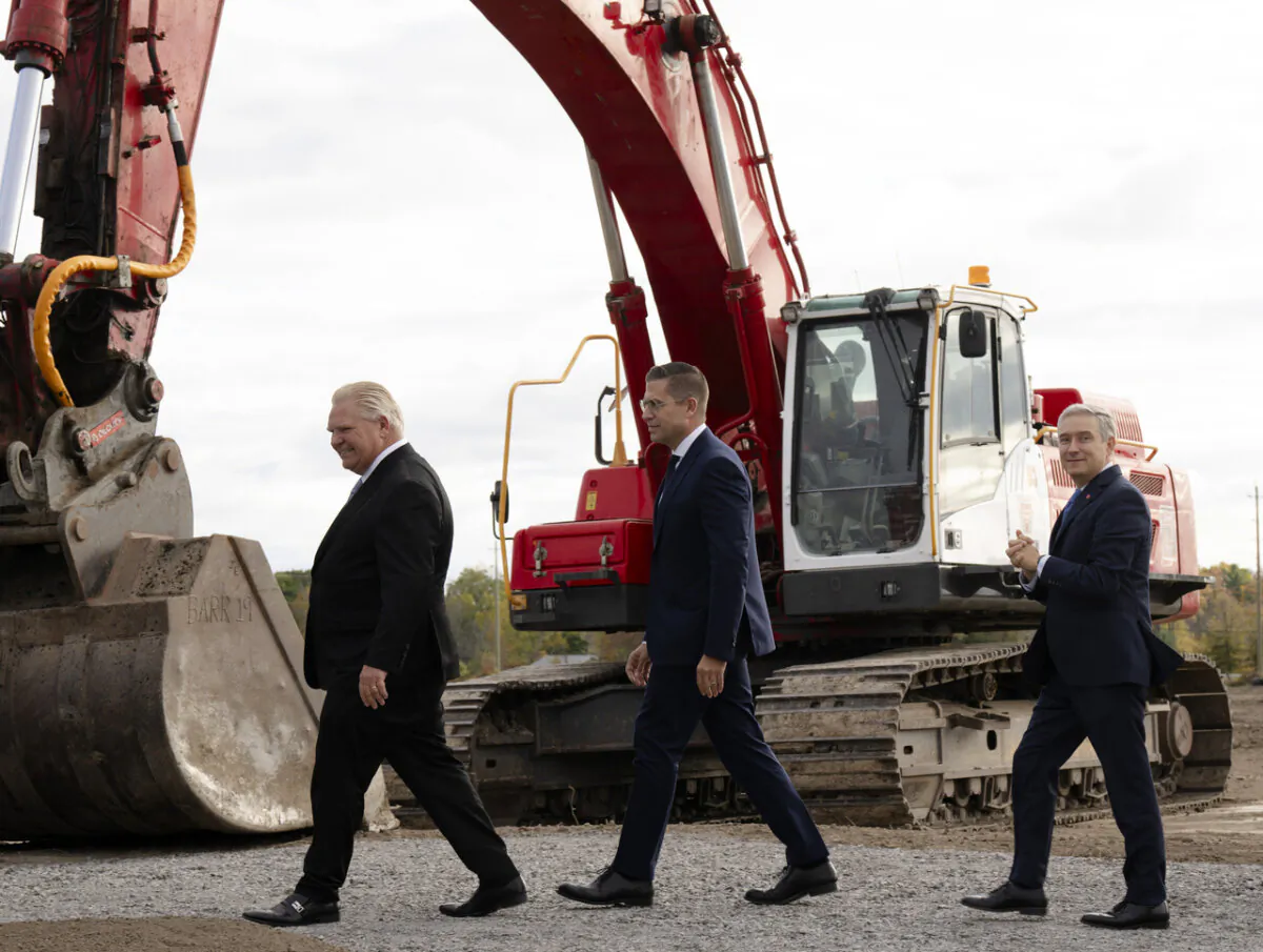 (L–R) Ontario Premier Doug Ford, Umicore CEO Mathias Miedreich, and Industry Minister François-Philippe Champagne make their way past heavy equipment to a ceremonial ground-breaking ceremony, in Millhaven, Ont., on Oct. 16, 2023. (The Canadian Press/Adrian Wyld)