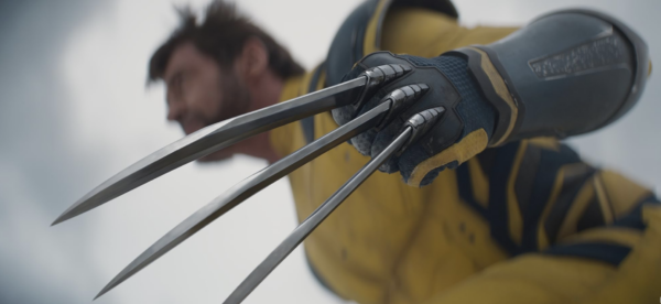 Man in yellow suit with giant metal claws in DEADPOOL &WOLVERINE 