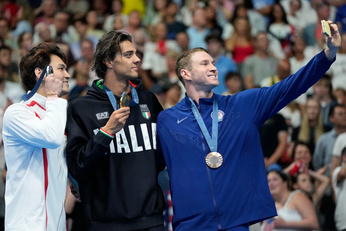 Gold medalist Thomas Ceccon of Italy stands on the podium with silver medalist Xu Jiayu (L) of China, and bronze medalist Ryan Murphy (R) of the United States, for a selfie following the men's 100-meter backstroke final at the 2024 Summer Olympics in Nanterre, France, on July 29, 2024. (Matthias Schrader/AP Photo)
