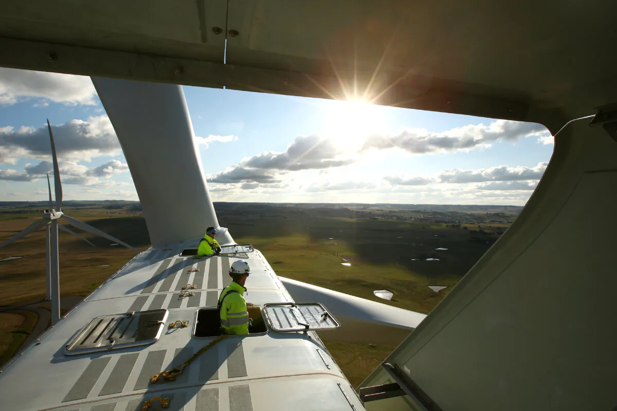 Vestas service technicians look out on the view from the hatches on the top of a wind turbine in Taralga, Australia, on Aug. 31, 2015. (Mark Kolbe/Getty Images)