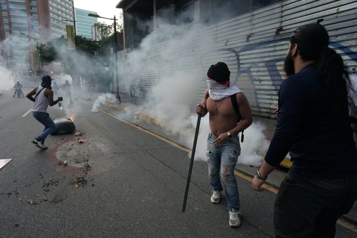 Protesters run to take cover from tear gas as Venezuelan opposition supporters protest following the announcement by the National Electoral Council that Venezuela's President Nicolás Maduro had won the presidential election, in Caracas, Venezuela, on July 29, 2024. (Alexandre Meneghini / Reuters)
