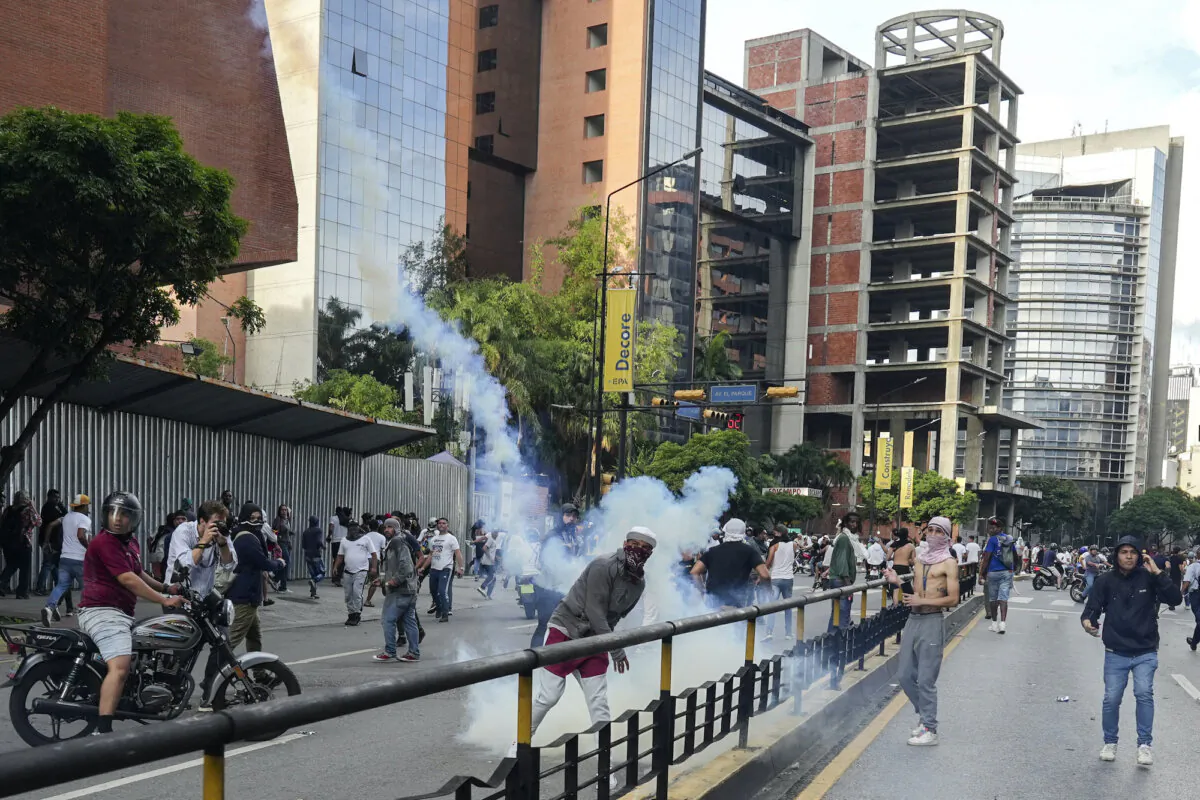A protester throws back a tear gas canister as Venezuelan opposition supporters protest in Caracas, Venezuela, on July 29, 2024. (Alexandre Meneghini/Reuters)