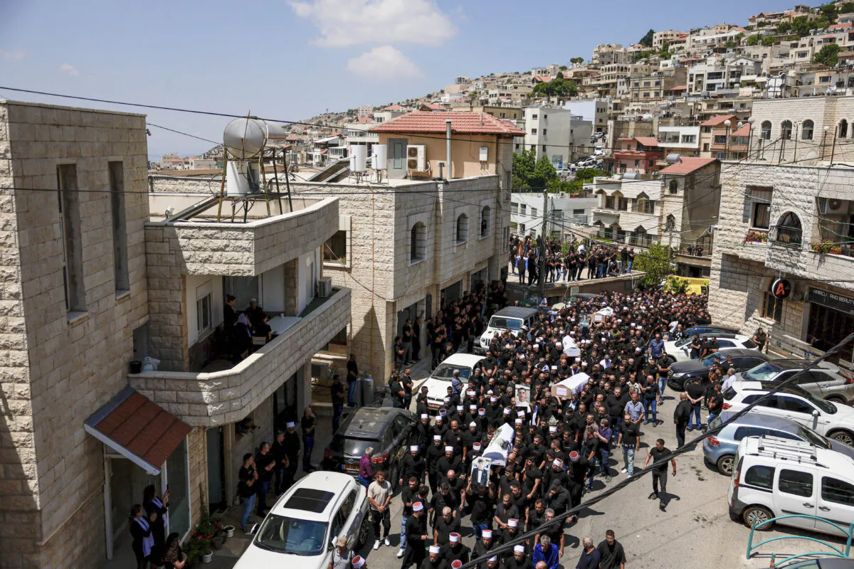 Mourners carry coffins, during the funeral of children who were killed at a soccer pitch by a rocket Israel says was fired from Lebanon, in Majdal Shams, a Druze village in Golan Heights, on July 28, 2024. (Ammar Awad/Reuters)