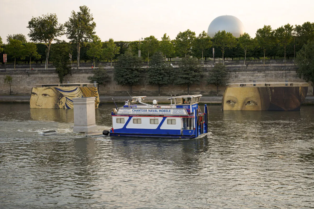 A boat sails past reproductions of artworks decorating the banks of the River Seineat the 2024 Summer Olympics in Paris, France, on July 30, 2024. (Dar Yasin/AP Photo)