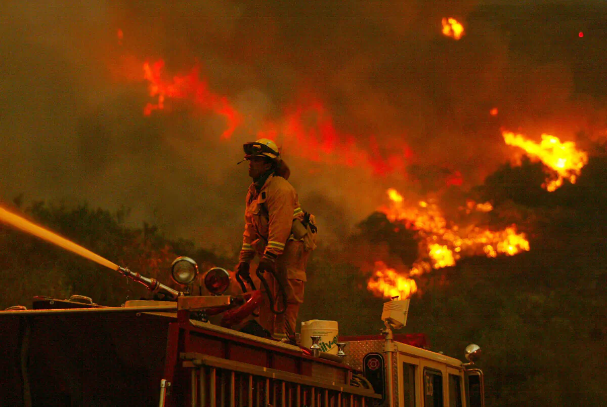 A firefighter battles a portion of the Cedar Fire using a water spout from atop a fire truck near Lakeside in San Diego on Oct. 27, 2003. (Donald Miralle/Getty Images)